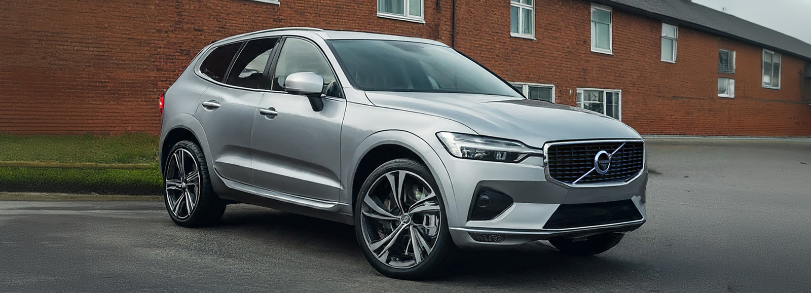 A Silver Volvo SUV parked in front of a brick building